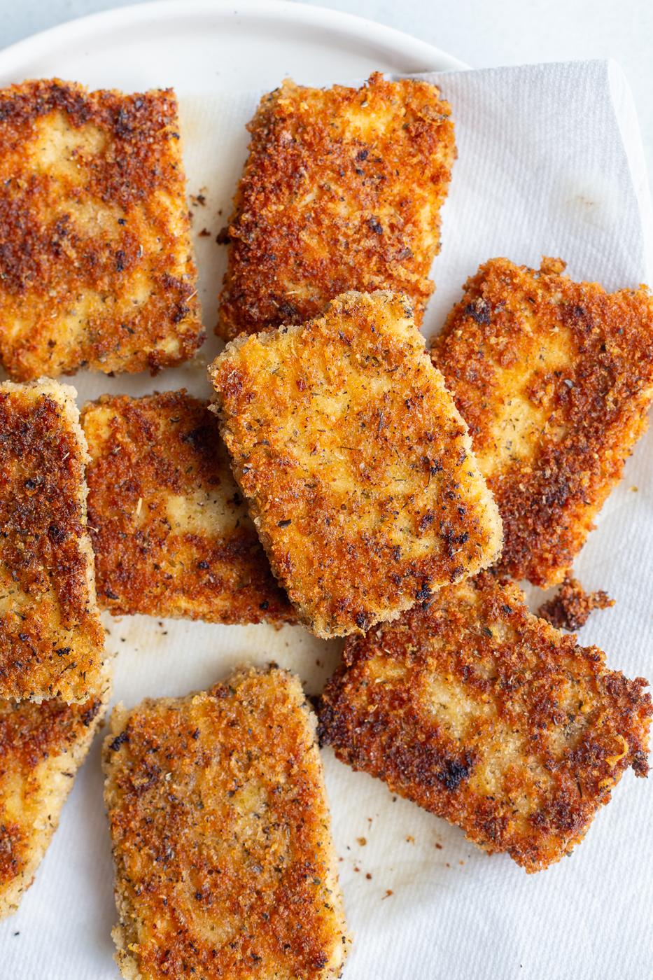 Cooked tofu cutlets on a paper towel lined plate.