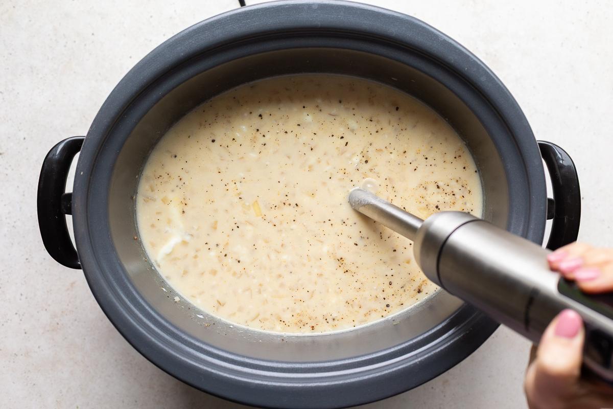 immersion blender stuck into a slow cooker to blend up potato soup