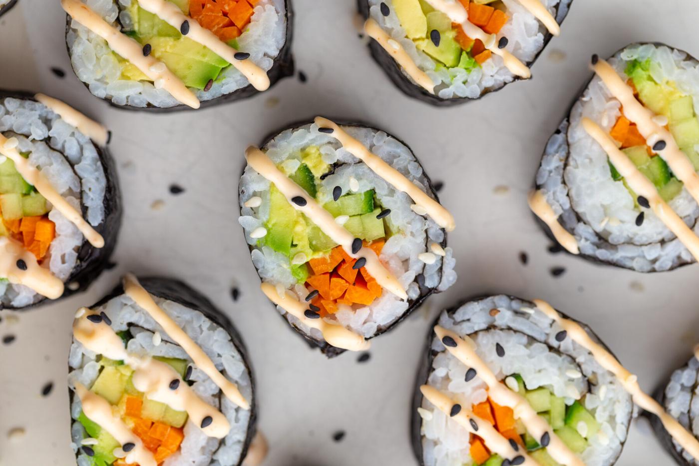 Cucumber roll filled with avocado and pickled carrot and drizzled with spicy mayo.