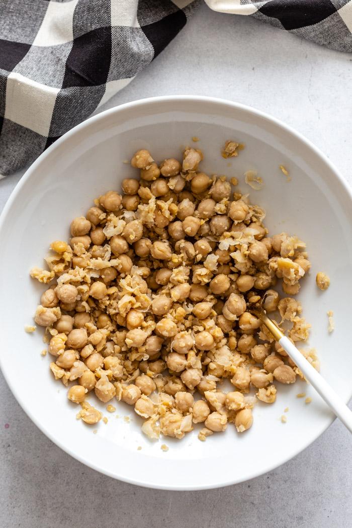 large white bowl filled with partially smashed chickpeas