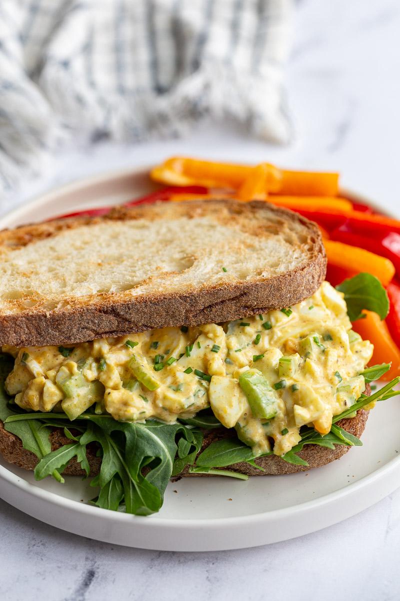curried egg salad on toast with arugula on a plate