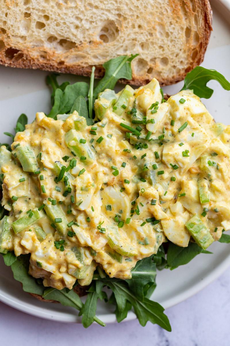 curried egg salad on toast with arugula on a plate