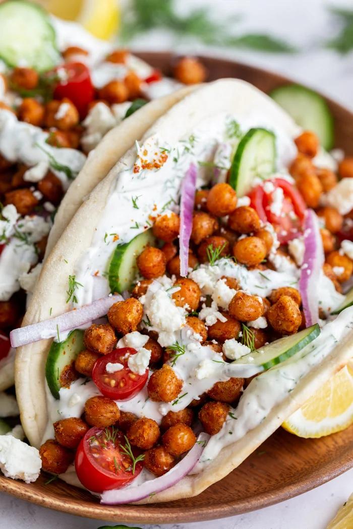 gyro made with crispy chickeas topped with red onion and feta cheese. on a wood plate