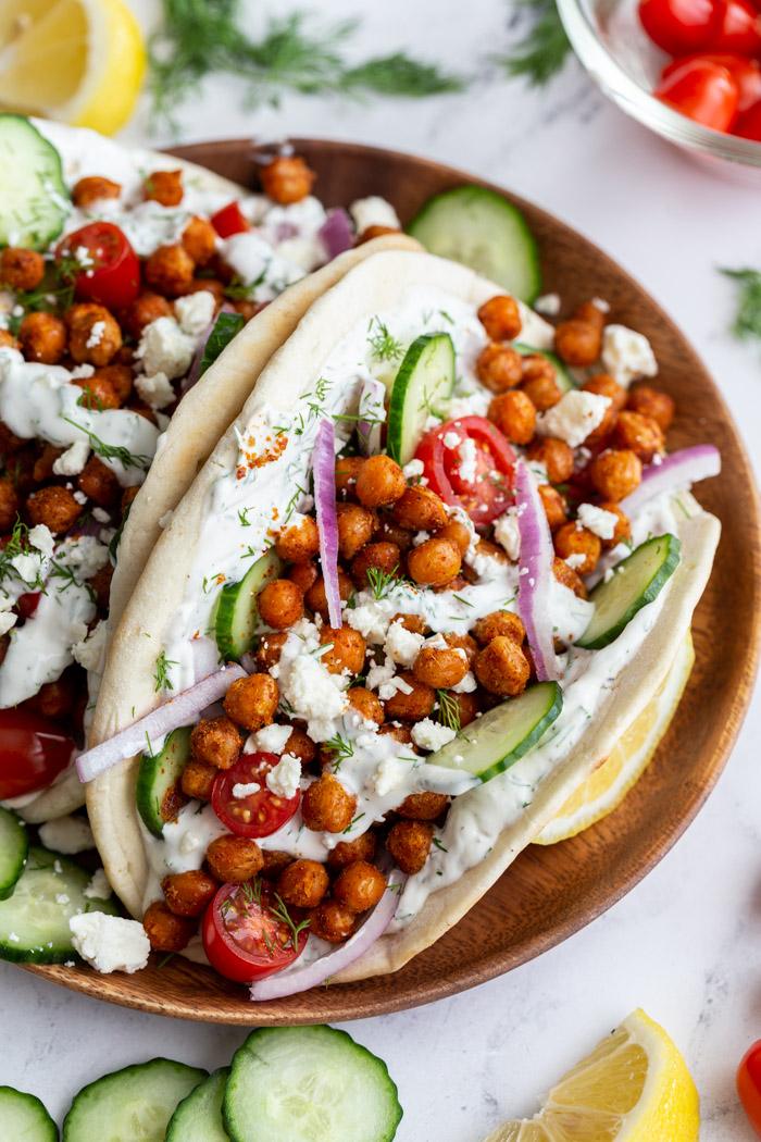 gyro made with crispy chickeas topped with red onion and feta cheese. on a wood plate