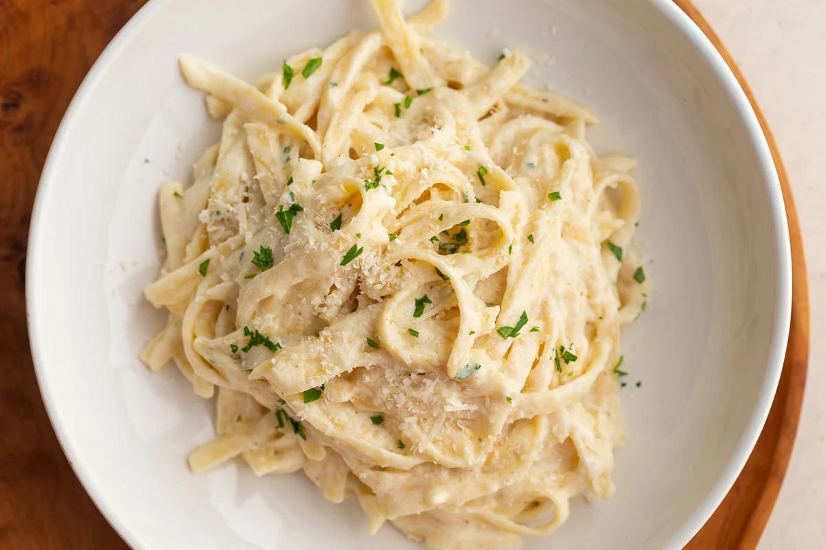 large bowl of fettuccini alfredo from-scratch topped with fresh parsley