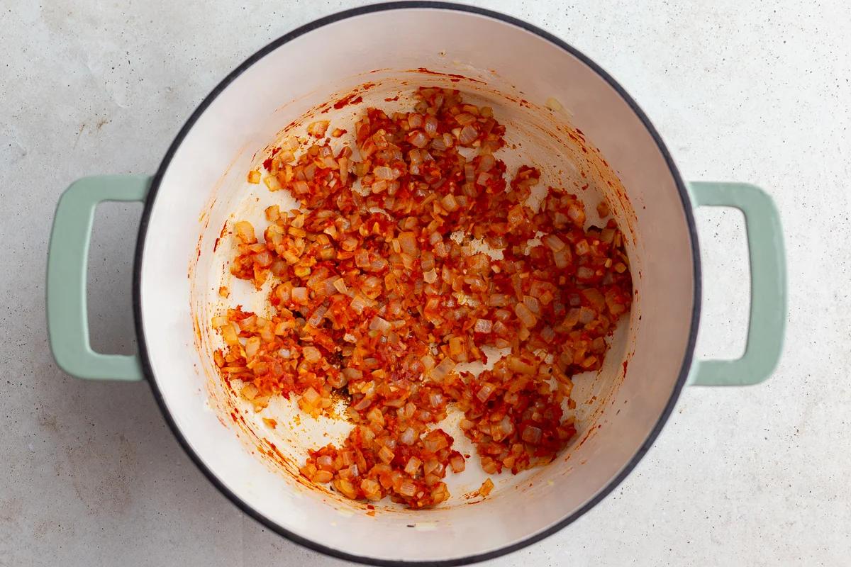 sauteed onion and garlic in a large pot with tomato paste mixed in