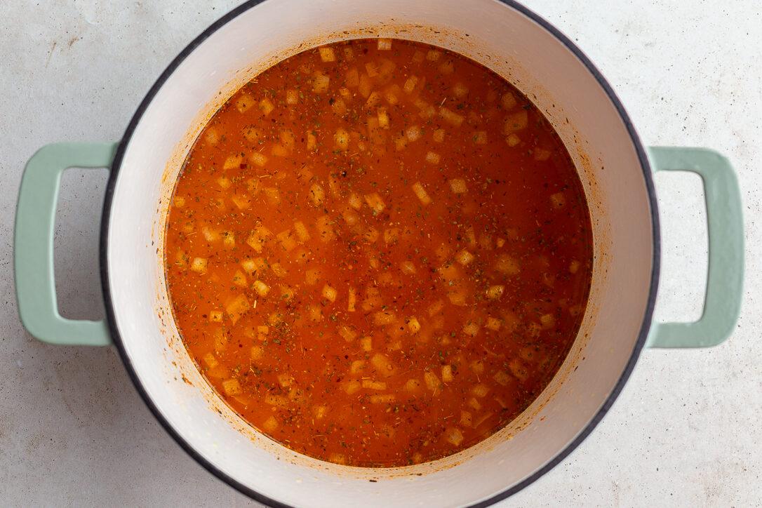 broth in a large pot with onion floating in it