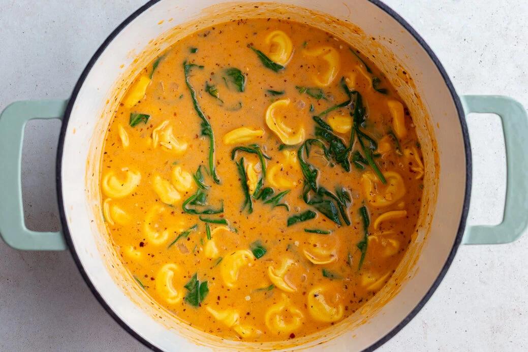 creamy tortellini soup in a large pot where you can see the tortellini and spinach floating at the top