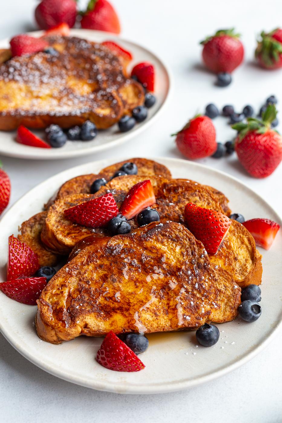 french toast on a plate with fresh strawberries and blueberries