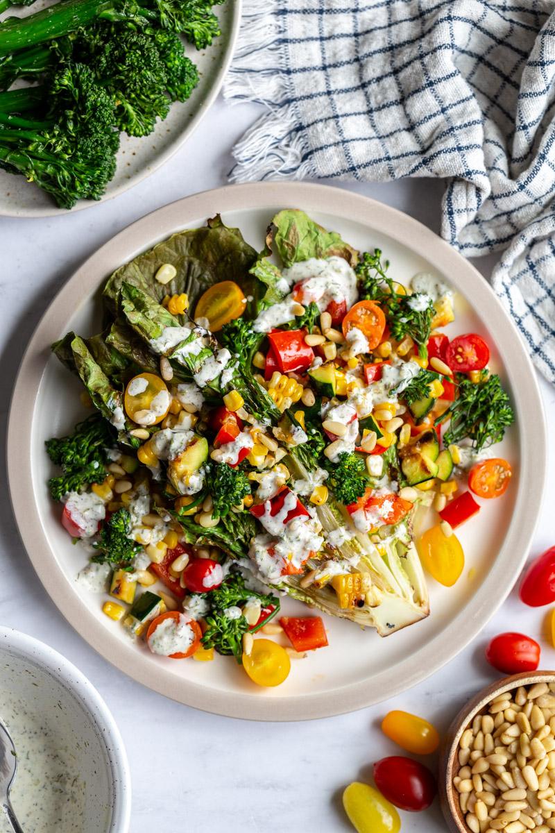 grilled romaine lettuce topped with mixed veggies and a white salad dressing