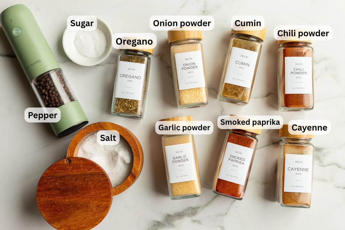 ingredients need to make fajita seasoning laid out on a flat surface so you can see the names of the spices including smoked paprika, chili powder, onion powder, garlic powder, salt and pepper