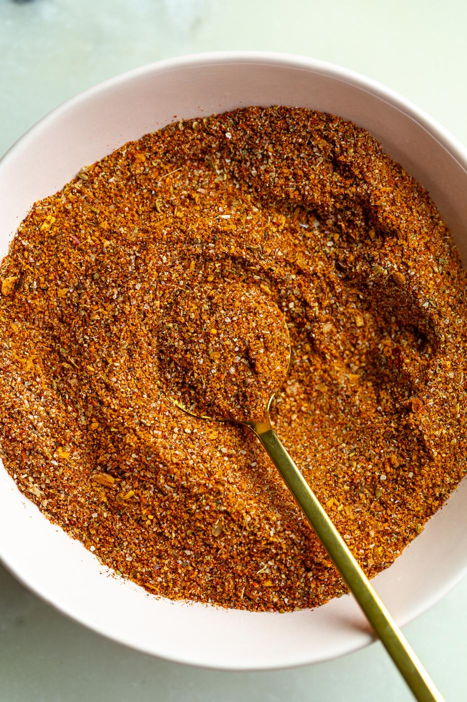 from-scratch fajita seasoning in a small bow with a gold spoon dipped in it
