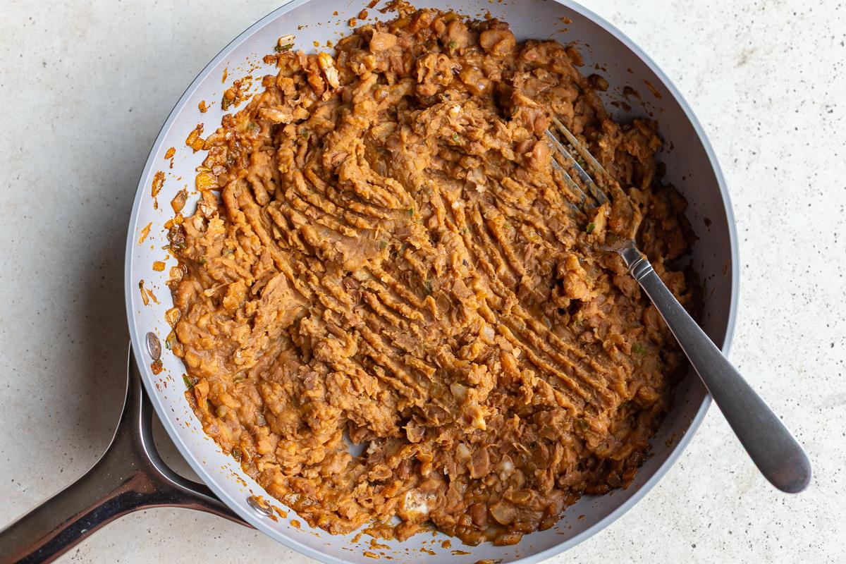 how to cook this refried beans recipe: add in the cooked pinto beans and mash them