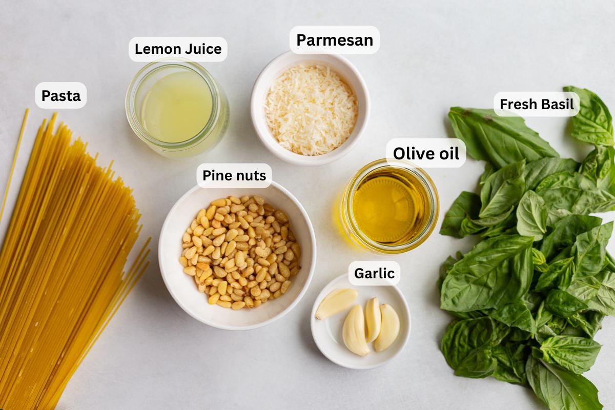 ingredients needed to make kitchen-made pesto pasta including pasta, garlic, lemon, pine nuts, and basil