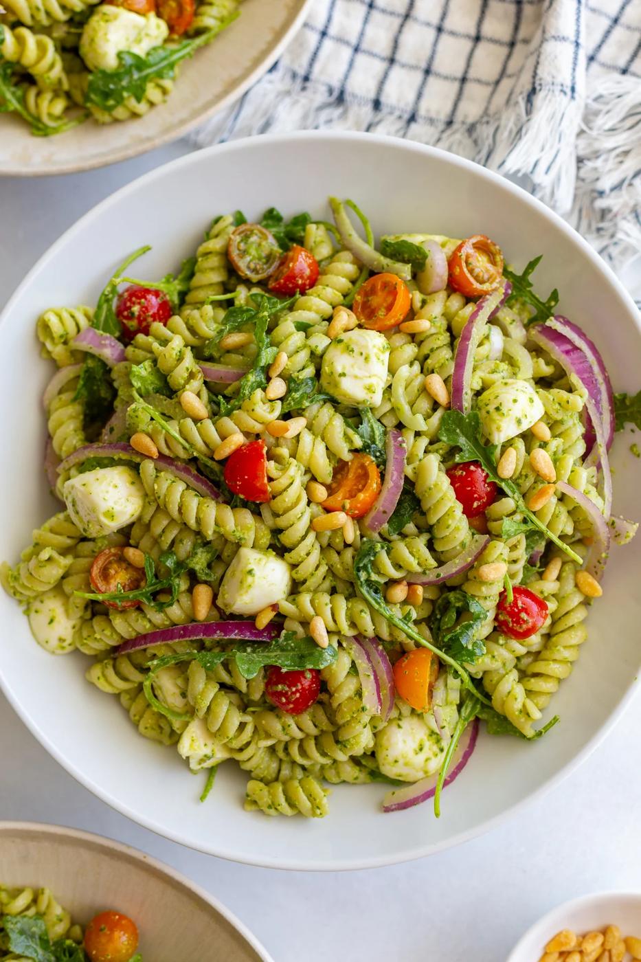 Straightforward Pesto Pasta Salad in a large bowl with a napkin in the corner of the shot