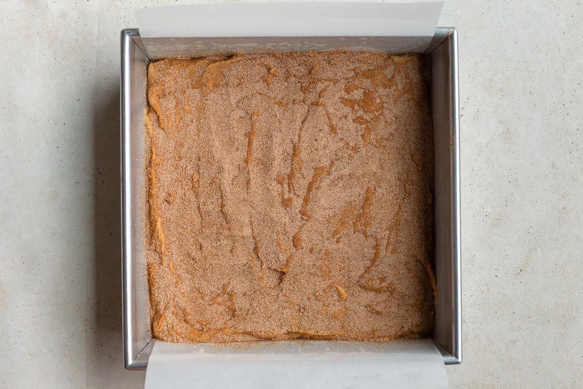 how to make snickerdoodle blondie bars: step 5 add the mixture to a 9x9 pan and cover with cinnamon sugar