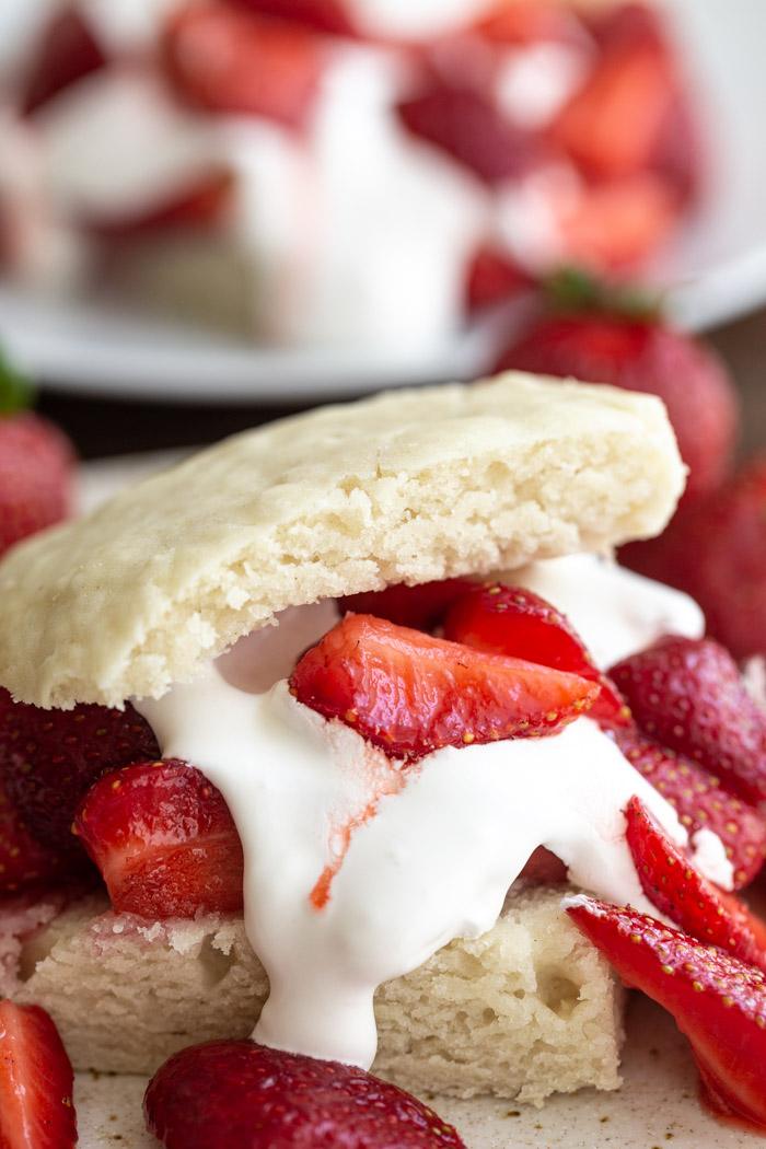 up close shot of unfussy strawberry shortcake that's topped with whipped cream and quartered strawberries