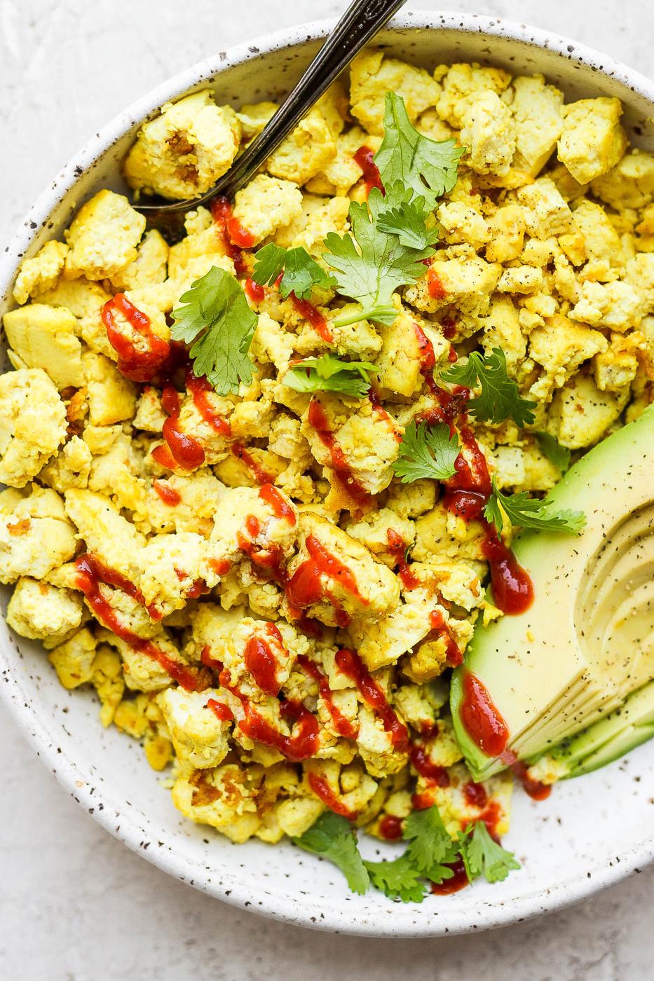 Tofu scrambled 'eggs' served with avocado slices.