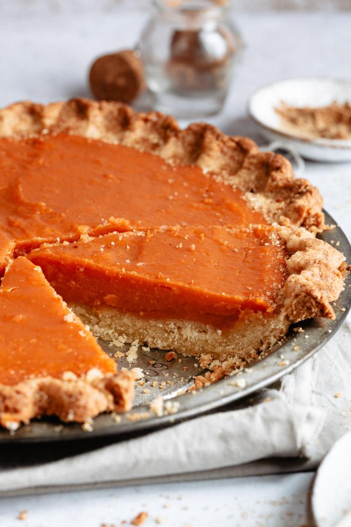 side shot of a sweet potato pie with a slice taken out