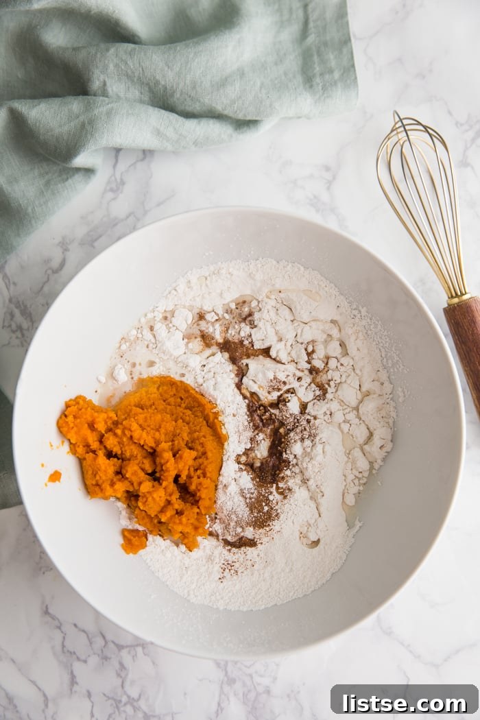 Spiced Pumpkin Donut Delights 5 Dry ingredients for pumpkin donuts in a large white bowl, ready to be whisked.