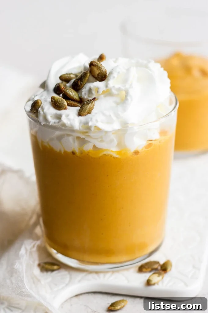 Pumpkin smoothie topped with whipped cream and pumpkin seeds, inviting a festive autumn mood.