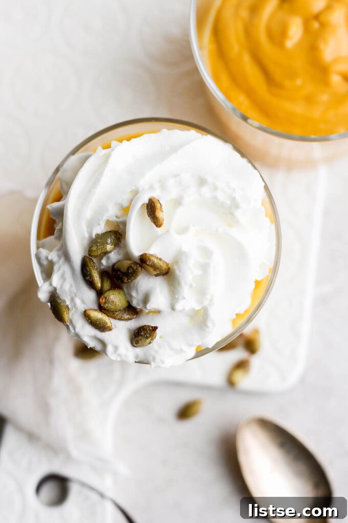 Smoothie with a whipped topping, garnished with a light dusting of spice.