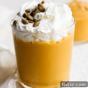 Pumpkin smoothie topped with whipped cream and pumpkin seeds.