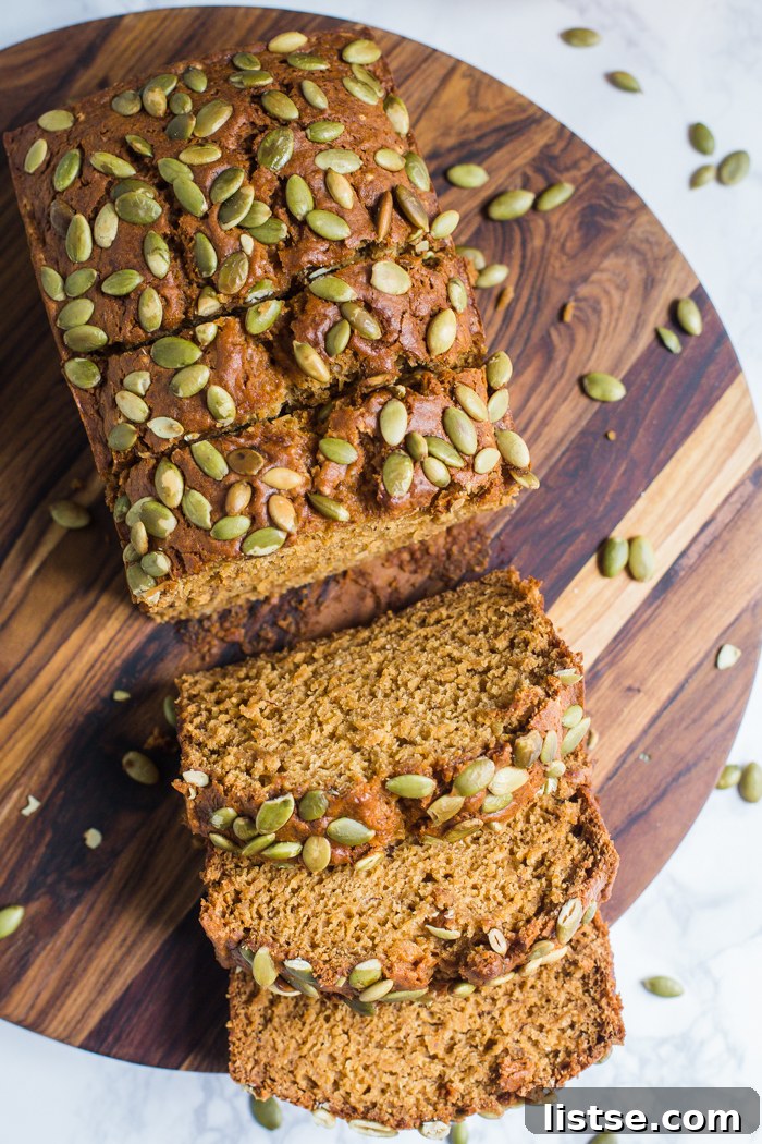 Plant-Based Pumpkin Spice Loaf 5 An open slice of vegan pumpkin bread adorned with pepitas, set against a cozy autumn backdrop with a pumpkin.