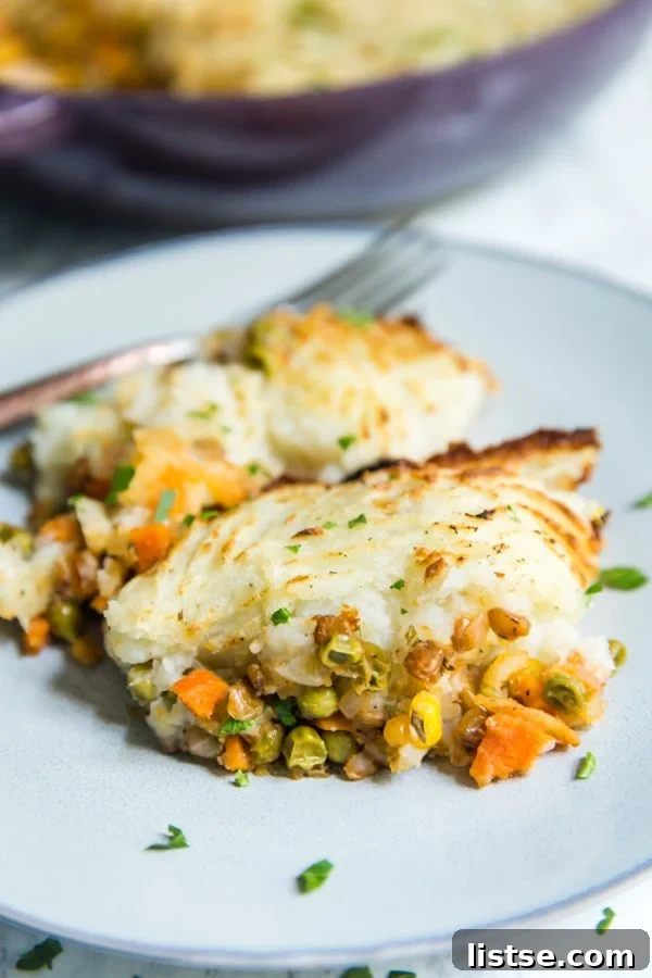 A serving of lentil shepherd's pie, generously covered in creamy mashed potatoes, is presented on a delicate light blue plate. The texture of the mashed potatoes is visibly soft and inviting, perfectly complementing the hearty filling.