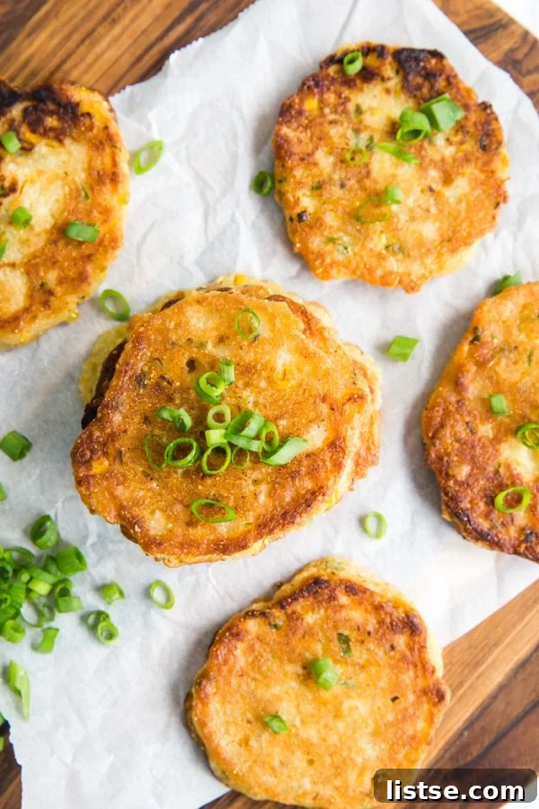 Freshly fried Vegan Corn Fritters stacked on a serving plate with green garnish.