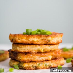 Close-up of golden Vegan Corn Fritters with green garnish.
