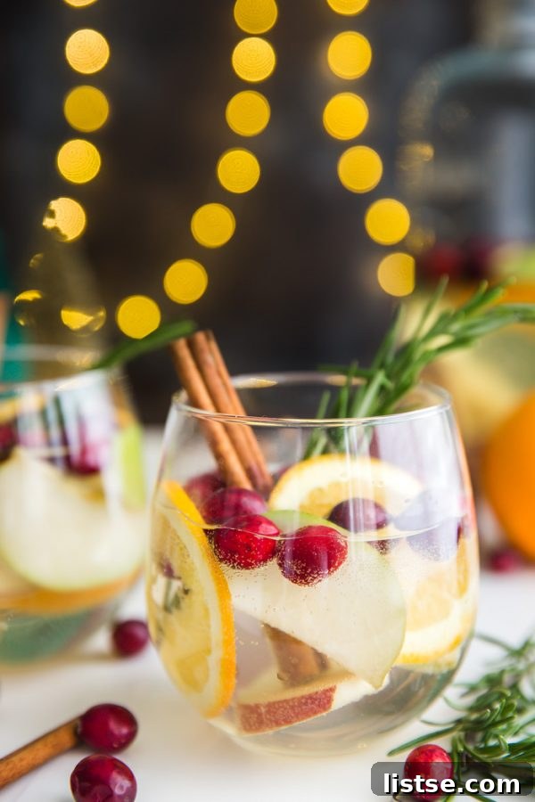 Refreshing Holiday Sangria ready to serve, garnished with fresh fruit and rosemary.
