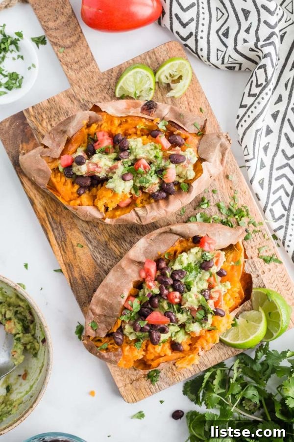 Two halves of a Guacamole Stuffed Sweet Potato, showcasing the creamy guacamole and black beans on a perfectly baked sweet potato.