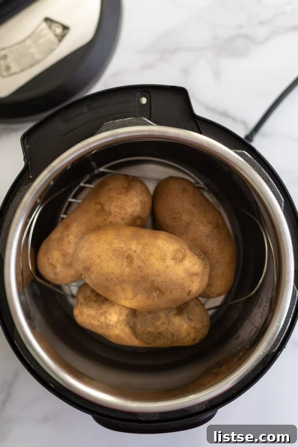Fluffy Instant Pot Baked Potatoes 3 Four wholesome russet potatoes neatly stacked inside the gleaming stainless steel pot of an Instant Pot pressure cooker, ready for cooking.