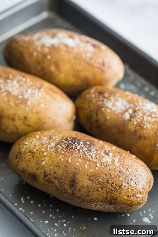 Fluffy Instant Pot Baked Potatoes 4 Several perfectly salted russet potatoes resting on a baking sheet, showcasing their potential for crispy skins after a quick broil, a delicious complement to Instant Pot preparation.