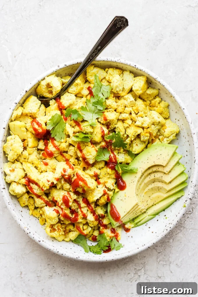 Effortless Vegan Scramble 2 Delicious and healthy tofu scramble topped with ketchup and fresh avocado slices, served for a vegan breakfast.