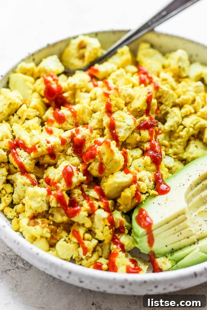 Effortless Vegan Scramble 3 Close-up of fluffy vegan 'eggs' made from seasoned tofu, garnished with a dollop of ketchup, ready for a wholesome meal.