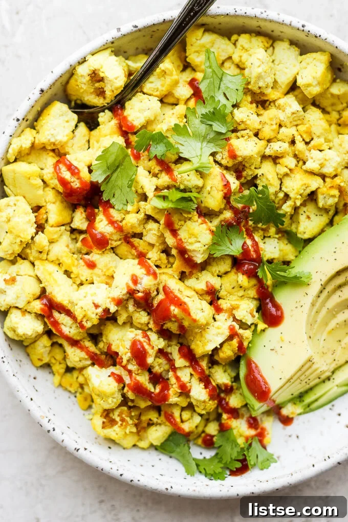 Effortless Vegan Scramble 8 A serving of vibrant tofu scrambled 'eggs' presented with fresh avocado slices and a sprinkle of herbs, perfect for a healthy breakfast.