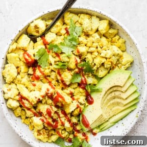 Tofu scramble topped with ketchup and served with avocado.
