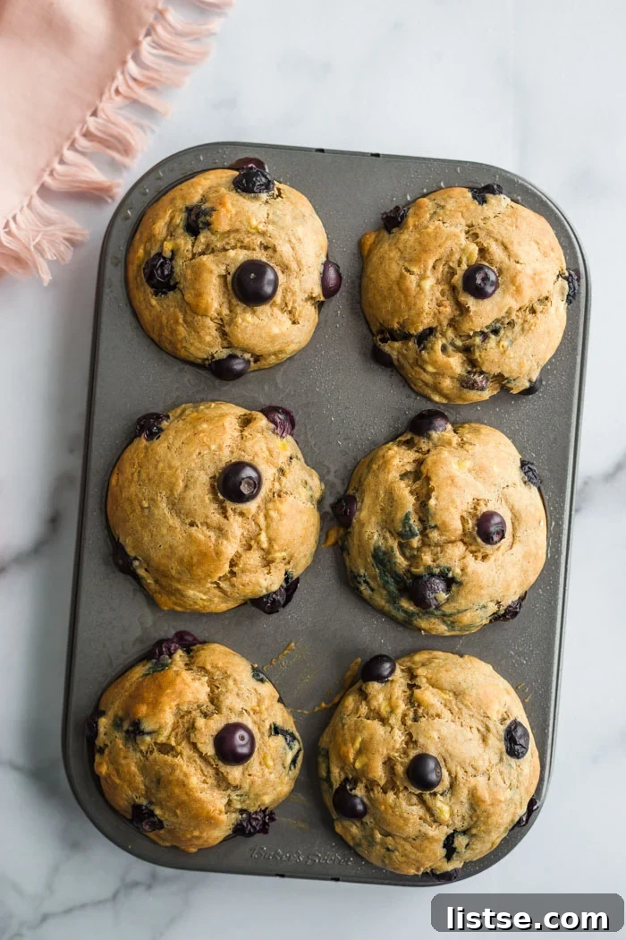 Six perfectly baked vegan blueberry muffins arranged on a elegant marble board.
