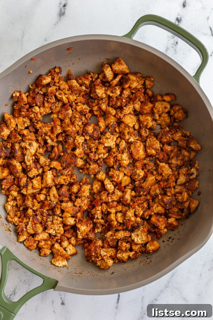 Effortless Tofu Taco Bliss 3 Close-up of perfectly browned and seasoned tofu taco meat sizzling in a nonstick skillet, showing crispy edges and a rich color.