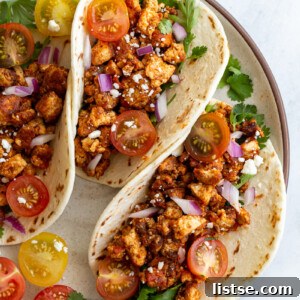 Effortless Tofu Taco Bliss 10 3 flour tortilla filled with tofu taco meat and topped with cherry tomatoes, cilantro, onion, and feta