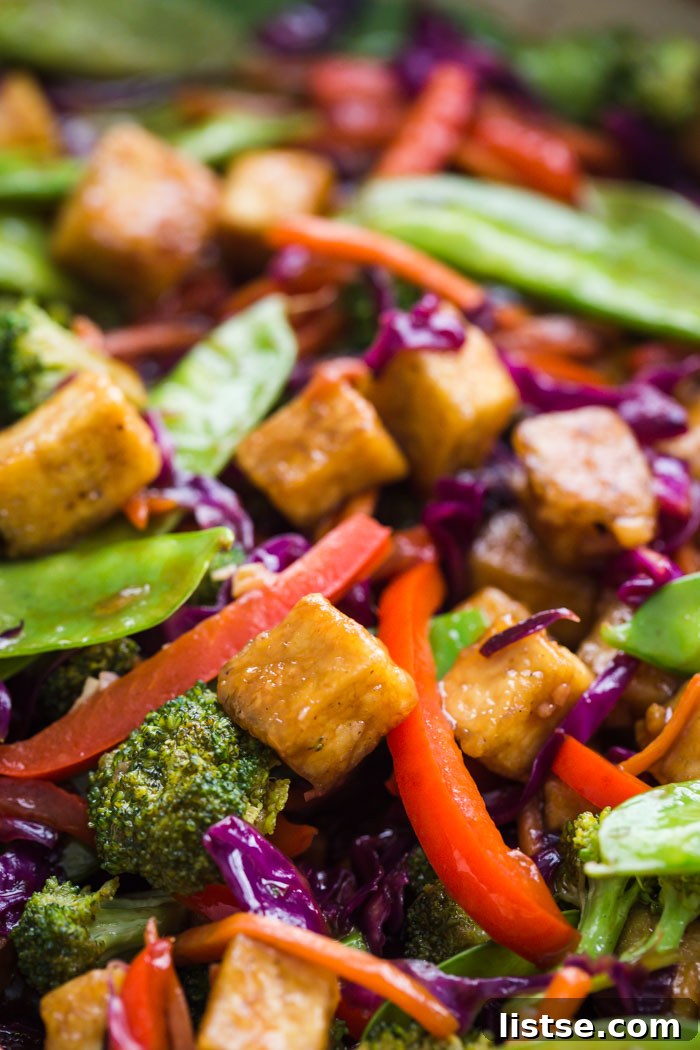 Close-up view of the tofu and vegetable stir fry simmering in a large skillet, coated in sauce.