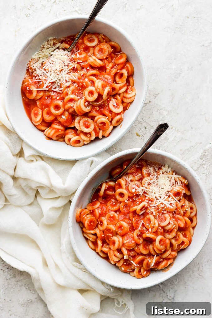 DIY Pasta Hoops 2 Two white bowls filled with homemade spaghettios, garnished with a sprinkle of fresh herbs.