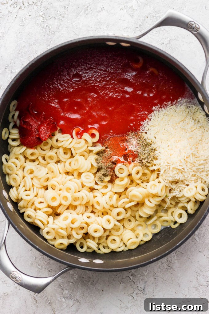 DIY Pasta Hoops 6 The process of combining cooked pasta with the rich tomato sauce and a sprinkle of cheese in a large cooking pot.