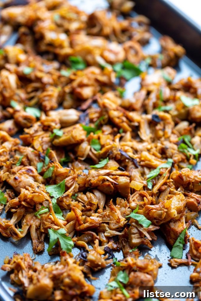 Shredded jackfruit carnitas on a baking tray and topped with cilantro, a savory vegan alternative.