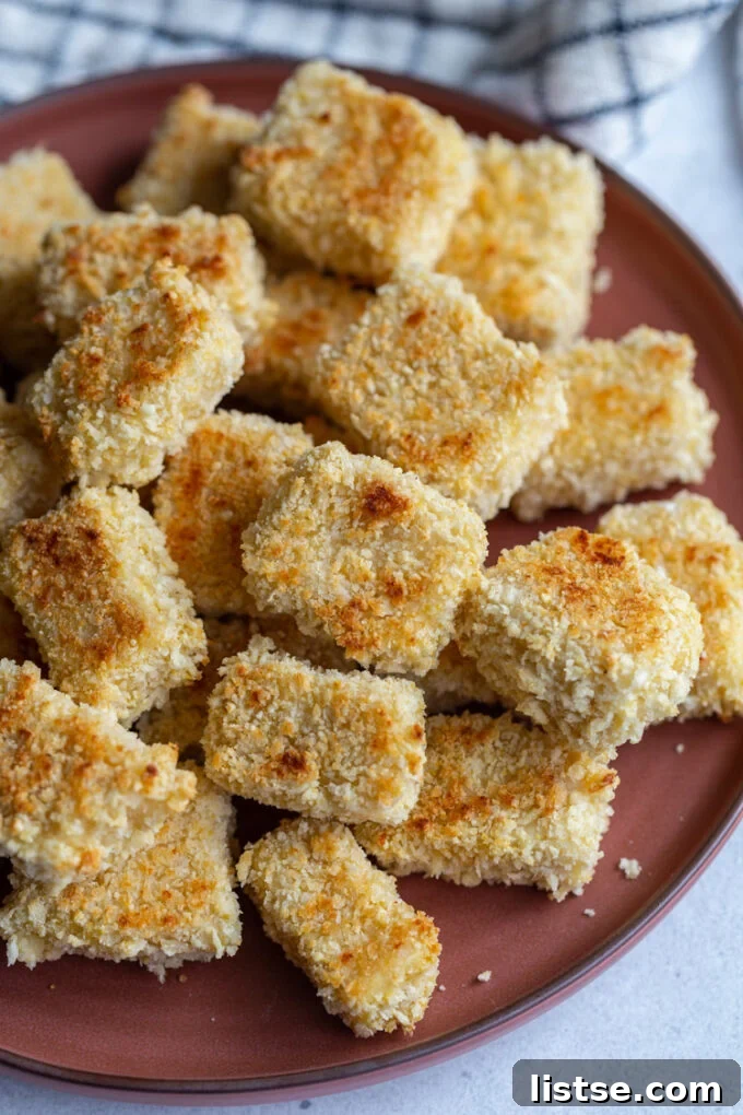 Panko crusted tofu cubes on a dark red plate, offering a crispy texture.