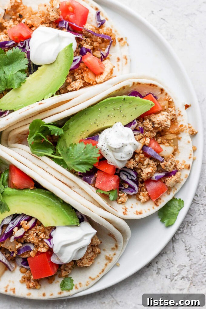 Three tortillas filled with vegan taco meat and fresh veggies, ready to eat.