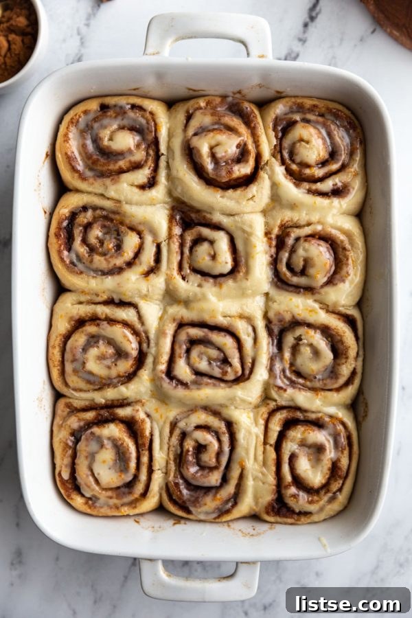 Close-up of freshly baked vegan cinnamon rolls, perfectly golden brown and generously topped with sweet white glaze.