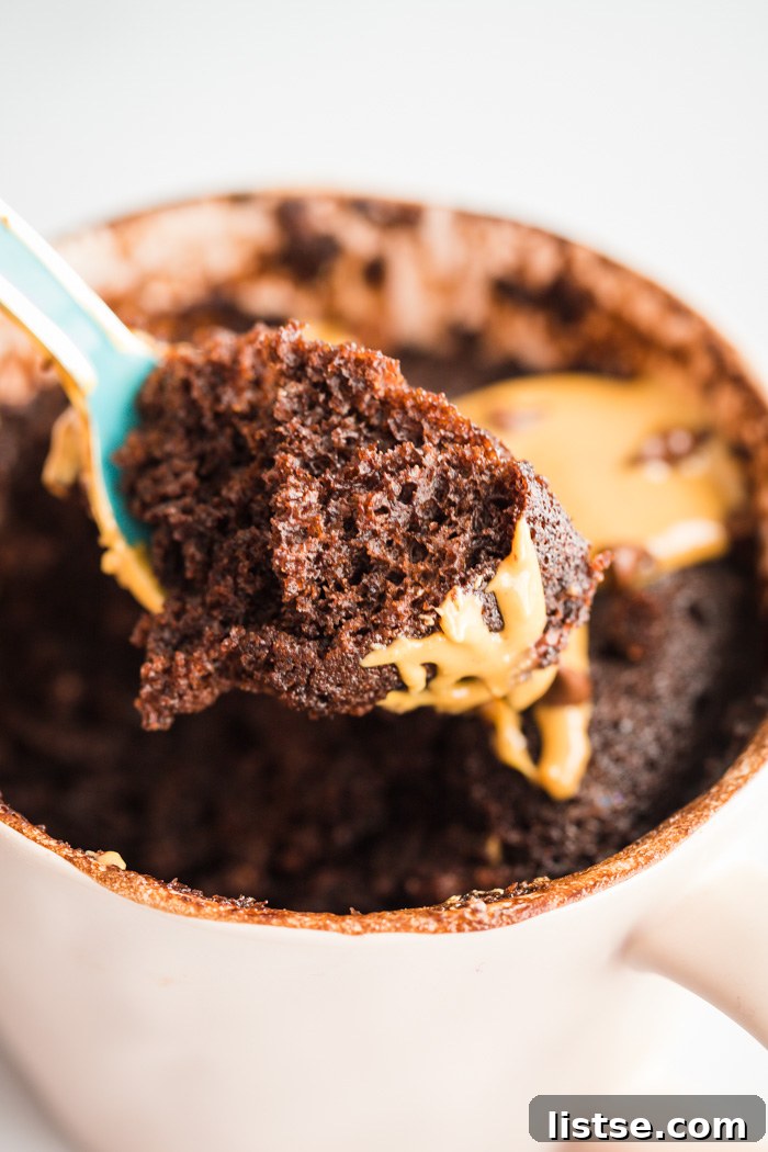 spoonful of fluffy chocolate cake from a mug, showing its soft texture